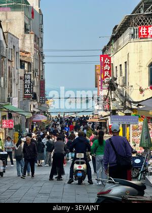 Eine überfüllte Fußgängerzone, die zum Ufer in Beihai, Guangxi, China führt, zeigt lokale Unternehmen, Touristen, Bewohner und Fischerboote Stockfoto
