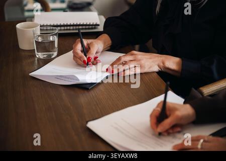 Nahaufnahme von Geschäftsfrauen, die Vertragsformulare im Sitzungssaal ausfüllen Stockfoto