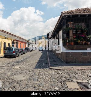 Malerische Kopfsteinpflasterstraße mit Blick auf das Wahrzeichen Santa Catalina Arch unter einem blauen Himmel in Antigua Guatemala Stockfoto