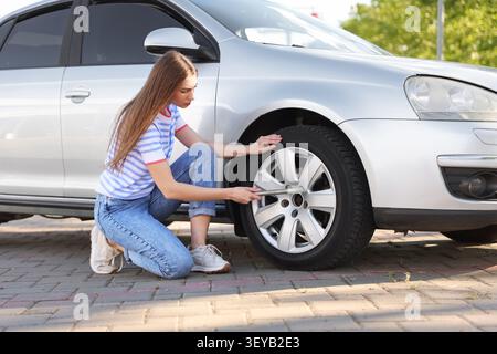 Frau wechselte im Auto draußen an sonnigem Tag den Reifen Stockfoto