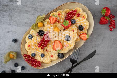 Overhead-Frühstückskomposition mit Waffelpfannkuchen mit frischen Beeren und saisonalem Obst Stockfoto
