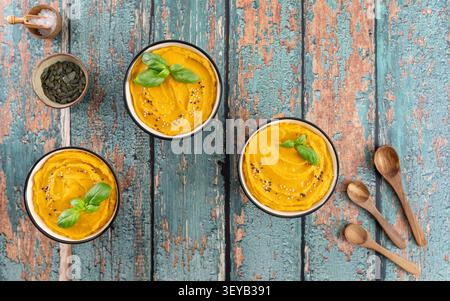 Überkopfkomposition aus cremiger Kürbissuppe garniert mit frischen Basilikumblättern Stockfoto