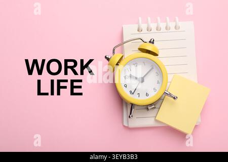 Work-Life-Balance. Wecker, Notizbuch- und Papiernotizen auf rosafarbenem Hintergrund, Draufsicht Stockfoto
