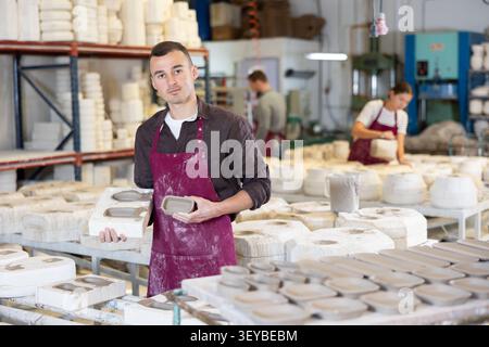 Junger Mann, der gegossene Tonformen zeigt Stockfoto