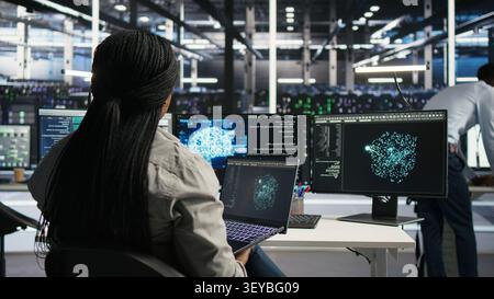 Der Administrator des Rechenzentrums verwendet einen Laptop, um Workloads des maschinellen Lernens zu verwalten, wobei er mit KI-Technologie und Hochleistungssystemen arbeitet. Stockfoto