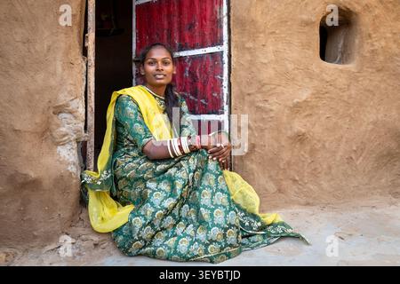 Junge Frau in traditioneller Kleidung sitzt in einem Eingang in Jaisalmer, Indien Stockfoto