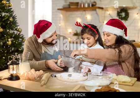 Fröhliche Familie backt Urlaubskekse zu Hause mit Tochter in festlicher Küche Stockfoto
