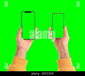 Hände, die zwei Smartphones mit grünen Bildschirmen halten Stockfoto