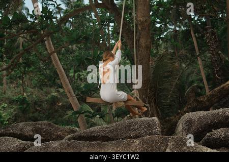 Frau in weißem Kleid, die auf dem tropischen Wald sitzt Stockfoto