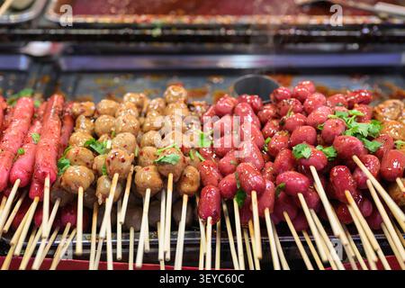 Eine lebendige, hochwinklige Nahaufnahme zeigt eine bunte Auswahl an beliebten thailändischen Street Food-Köstlichkeiten, die bei einer Nacht ordentlich auf einem Metalltablett angeordnet sind Stockfoto