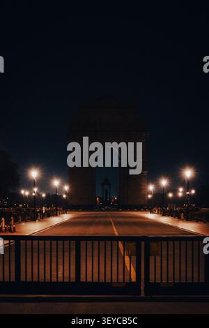 India Gate bei Nacht beleuchtet mit einer leeren zeremoniellen Allee und glühenden Straßenlaternen in Neu-Delhi, Indien. Stockfoto
