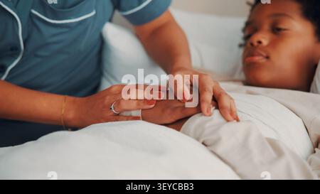 Mutter, Hände halten und Unterstützung für kranke Kind im Schlafzimmer, Liebe und Empathie für Sohn mit Grippe-Symptomen. Ruhe, Heim und Komfort für Kinder mit Kälte Stockfoto