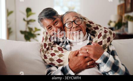 Lustig, umarmt und Porträt eines alten Paares auf Sofa zu Hause zusammen für Bindungen oder Ruhestand. Verbindung, Lachen und Liebe zu Senioren Stockfoto