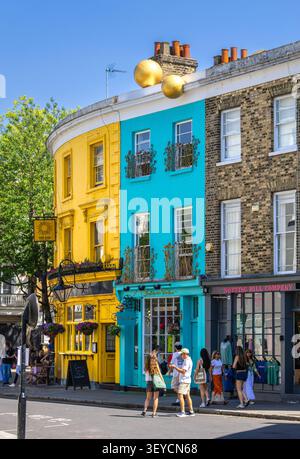 London, Vereinigtes Königreich - 25. Mai 2026: Bunte Reihe von Stadthäusern in Notting Hill, mit Fußgängern auf einer sonnigen Straße, mit hell bemalten Fassaden Stockfoto