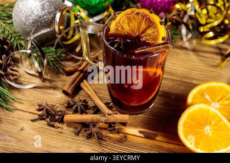 Weihnachtlicher Glühwein mit Gewürzen und Weihnachtsdekoration auf Holztisch Stockfoto