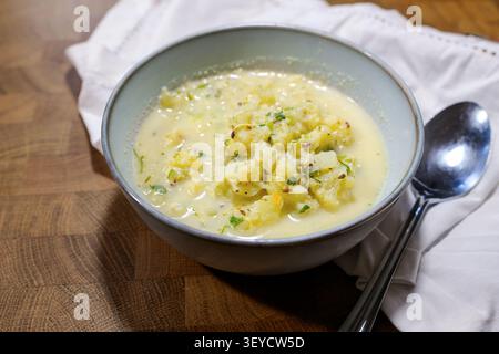 Blumenkohlsuppe mit Kräutern und Gewürzen in einer Schüssel, Serviette und Löffel auf einem rustikalen Holztisch, hausgemachte gesunde vegetarische Mahlzeit, ausgewählter Fokus, schmal Stockfoto