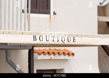 Boutique-Schild stationär, in der Gebäudefassade, mit Boutique-Schild, Gebäudewand, Fensterläden, mit Metall, lackiertem Holz, Ziegelfliesen Textur, von Stockfoto