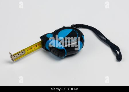 Hochauflösende Studioaufnahme eines modernen blau-schwarzen Maßbandes mit gelbem Bandmaß teilweise verlängert. Das kompakte ergonomische Design Stockfoto