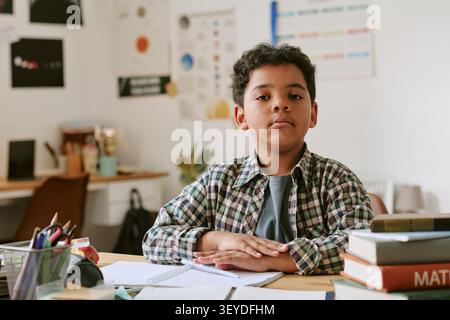 Porträt des Schwarzen Jungen, der am Schreibtisch für die Schulkampagne sitzt Stockfoto