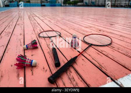 Niedrigwinkelaufnahme von Badminton-Schlägern und Federbällen auf pinkfarbenem Holzboden des Courts. Sommersport und aktiver Lebensstil. Stockfoto