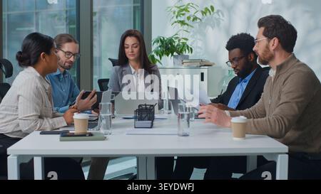 Führungskräfte aus multirassischen Geschäftsteams treffen sich an einem Konferenztisch, um Daten und Finanzstatistiken zu diskutieren und Dokumente mit Laptop zu analysieren. Multiethnische Arbeitnehmer Stockfoto