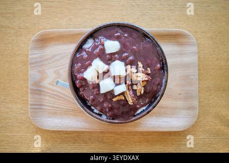 Asiatisches geraspeltes Eis-Dessert mit süßer hausgemachter Bohnenpaste, klebrigen Reiskuchen und getrockneten Fruchtscheiben auf einem Holztray. Ideal für Sommer-Café-Menüs. Stockfoto
