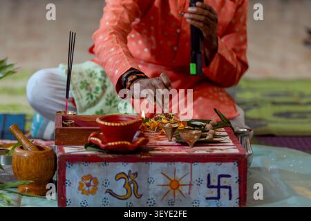 Der Hindupriester führt ein Puja-Ritual mit Opfergaben und brennenden Räucherstäbchen durch Stockfoto