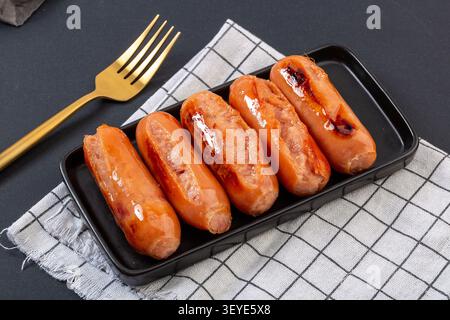 Gegrillte Premium-Schweinefleisch-Würstchen im taiwanesischen Stil auf Teller mit Holzbrett Stockfoto