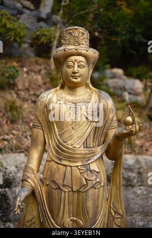 Stehende goldene Statue einer buddhistischen Gottheit oder Kuan-Yin-Figur im Otagi Nenbutsu-ji Tempel im Arashiyama-Bezirk von Kyoto, Japan Stockfoto