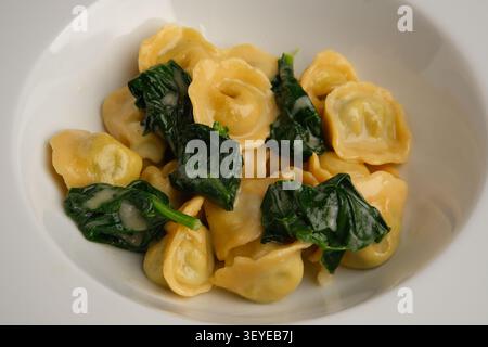 Gefüllte Pasta mit Spinat in einer weißen Schüssel, hausgemachte Hochglanzgerichte mit einfachem Licht Stockfoto