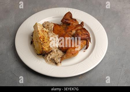 Gebratenes Hähnchen auf weißem Teller mit gegrilltem Kohl und cremiger Pilzsauce Stockfoto