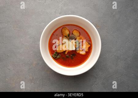 Weiße Schüssel Meeresfrüchte-Suppe mit Lachs, Muscheln, Garnelen und Zitrone auf Stein Stockfoto