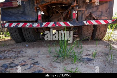 Rückansicht eines alten Muldenkippers, der mitten auf der Straße repariert wird, auf einer unbefestigten Straße. Stockfoto