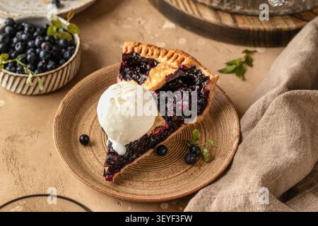 Scheibe Blaubeerkuchen mit einer Kugel Eis auf einer Keramikplatte auf braunem, texturiertem Tischhintergrund, traditionelles hausgemachtes Dessert Stockfoto