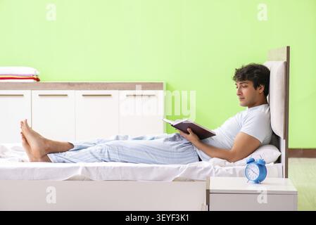 Jungen gutaussehenden Studenten lesen Buch im Bett Stockfoto