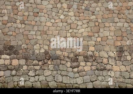 strukturierte Steinmauer, Hintergrund mit Farbtönen von Beige bis Braun, abgerundete raue Steine in einer nahtlosen Mauer Stockfoto