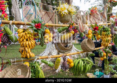 Farbenfrohe Ausstellung von lokal angebautem Obst, Gemüse und Kunsthandwerk auf einer Bambusstruktur, die die lebhafte landwirtschaftliche Ernte repräsentiert Stockfoto