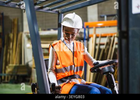 Weibliche Arbeiterin, die einen Gabelstapler im Holzlager bedient Stockfoto