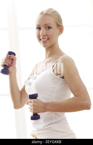 Schöne Frau, die Fitnessübungen mit Kurzhanteln macht Stockfoto