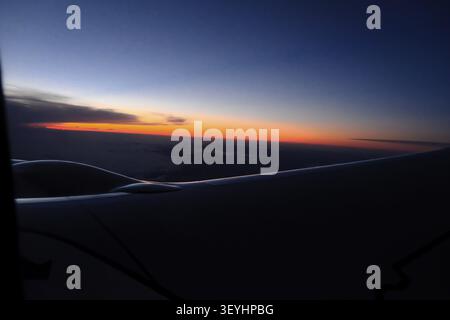 Sonnenaufgang über den Wolken, über der Silhouette des Flugzeugflügels, Flug Madrid - München Stockfoto
