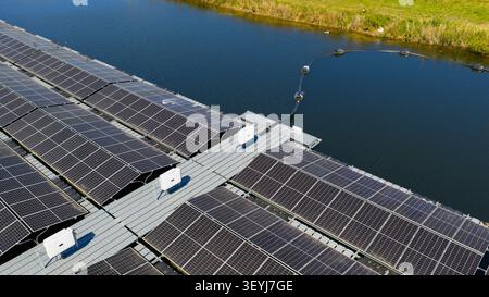 Luftaufnahme von schwimmenden Solarpaneelen auf einem Kanal mit Wechselrichtern und einem Eindämmungsarm in Zwolle, Overijssel, Niederlande. Stockfoto
