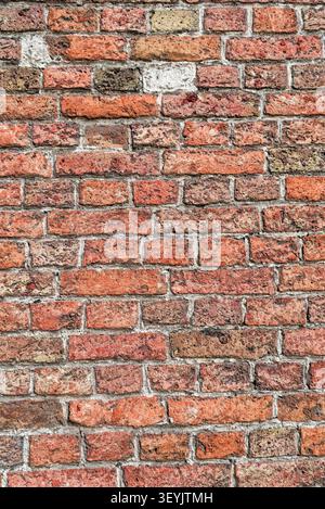 Vollrahmen-verwitterte rote Ziegelwand mit rauen Mörtelfugen und veralteter Oberfläche für Hintergrund- oder Texturanwendungen. Stockfoto