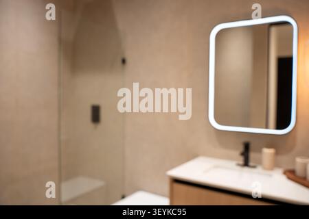 Verschwommener Blick auf das moderne Badezimmer mit beleuchtetem Spiegel. Stockfoto