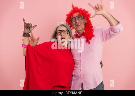 Lächelndes Seniorenpaar hat Spaß und zeigt Rock-and-Roll-Handgesten Stockfoto