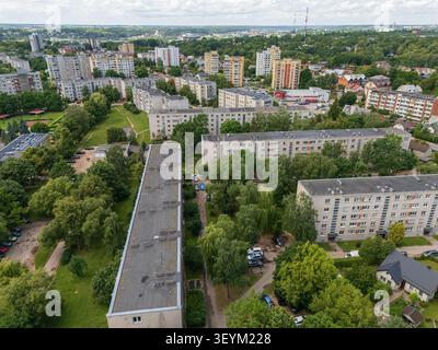 Aus der Vogelperspektive auf Wohnblocks aus der Sowjetzeit in Litauen, umgeben von grünen Bäumen und Sommervegetation, städtischem Wohnviertel und Stockfoto