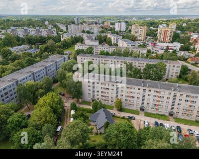 Aus der Vogelperspektive auf Wohnblocks aus der Sowjetzeit in Litauen, umgeben von grünen Bäumen und Sommervegetation, städtischem Wohnviertel und Stockfoto