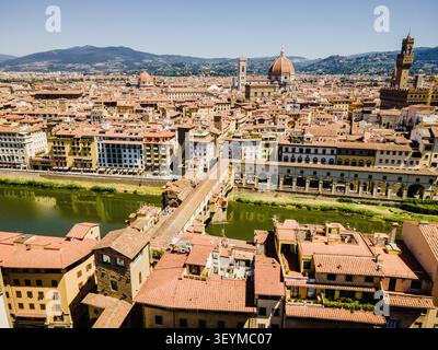 Blick aus der Vogelperspektive auf die berühmte Ponte Vecchio, die den Fluss Arno überspannt, mit der Kathedrale von Florenz und dem Palazzo Vecchio im Hintergrund, Florenz, Toskana, Stockfoto