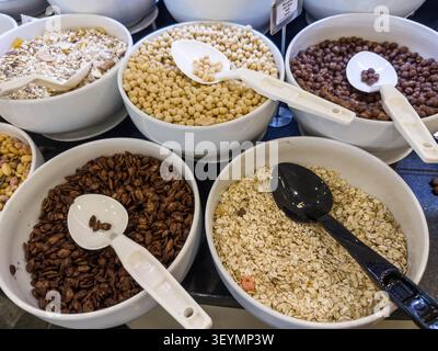 Verschiedene Frühstückszerealien Körner Nüsse in weißen Schüsseln mit Servierlöffeln auf dem Buffet-Tisch ausgestellte gesunde Auswahl an Speisen Ernährung Auswahl Morning Meal Konzept Stockfoto