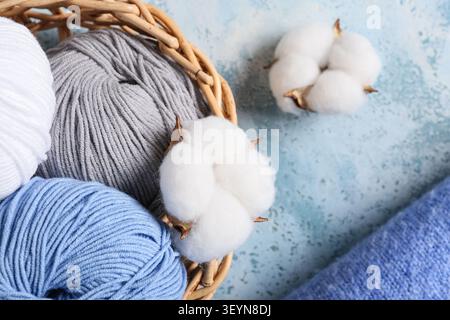 Korb mit Garnbällchen und Baumwollballen auf blauem Hintergrund Stockfoto