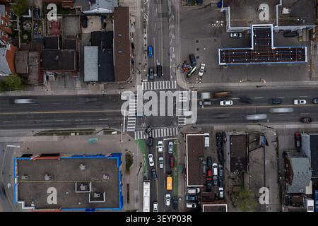 Von oben nach unten auf die geschäftige Kreuzung Toronto mit fahrenden Autos, markierten Wegen, Fahrradwegen, Dächern, Parkplätzen, und dicht städtisch Stockfoto